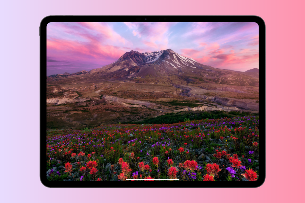 M4 iPad Pro med en baggrund med bjerge og blomster.